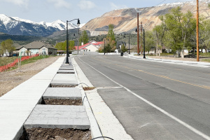 Sidewalk next to park strip alongside a roadway. Park strip is empty, awaiting fill dirt and plant material